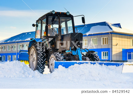 Tractor with shovel clears streets of snow. Snow removal and removal service in winter. Real scene 84529542