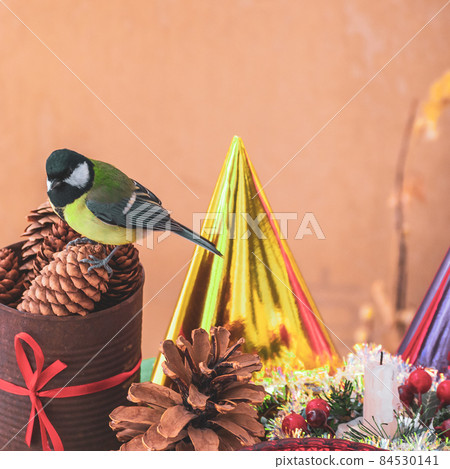 A titmouse bird eats on a table with Christmas decorations 84530141