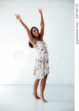 brunette woman in a summer dress in a white room brunette woman in a summer dress in a white room 84530233