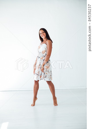 brunette woman in a summer dress in a white room 84530237