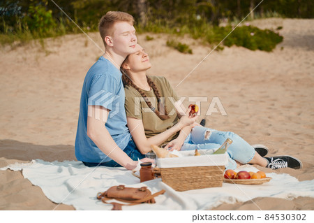 Picnic on beach with food and drinks. Young boy and girl sunbathing 84530302
