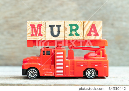 Fire ladder truck hold letter block in word mura on wood background Fire ladder truck hold letter block in word mura on wood background 84530442