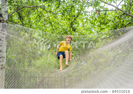 practice nets playground. boy plays in the playground shielded with a protective safety net. concept of children on line, kid in social networks. blurred background, blurred motion due to the concept 84531018