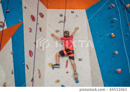 Boy at the climbing wall without a helmet, danger at the climbing wall 84531063