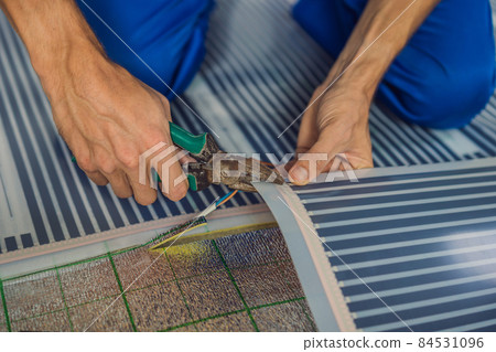 Master installs film warm floor in the room. Floor heating installation Master installs film warm floor in the room. Floor heating installation 84531096