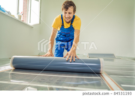Master installs film warm floor in the room. Floor heating installation 84531193