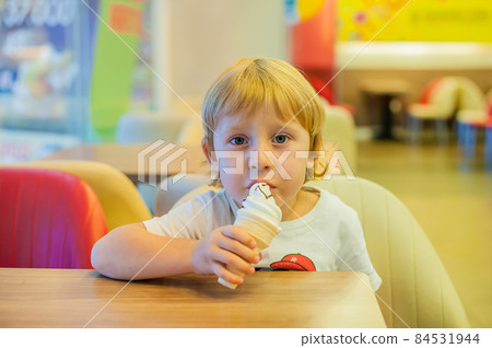 Little blond toddler child eating vanilla ice cream. 84531944