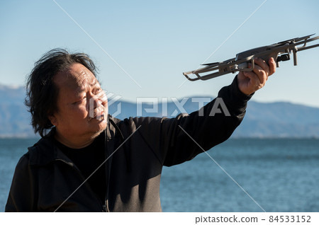 An uncle who checks his hobby drone with a doy face ... With Lake Biwa in Shiga prefecture in the background. An uncle who checks his hobby drone with a doy face ... With Lake Biwa in Shiga prefecture in the background. 84533152