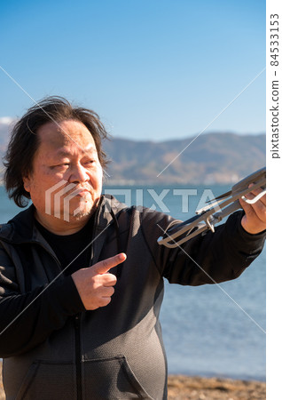 用娃娃臉檢查他的業餘愛好無人機的叔叔......以滋賀縣的琵琶湖為背景。 用娃娃臉檢查他的業餘愛好無人機的叔叔......以滋賀縣的琵琶湖為背景。 84533153