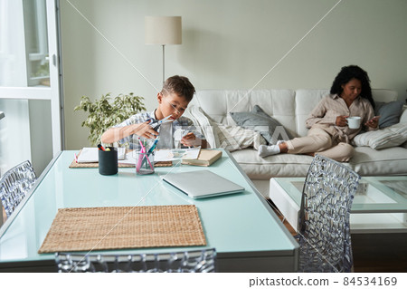 Black boy cut paper and mother use smartphone 84534169