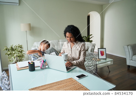 Black mother using laptop and child crafting Black mother using laptop and child crafting 84534170
