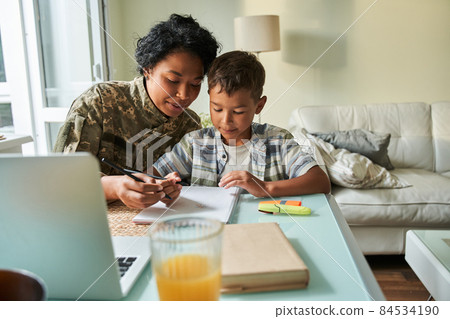 Black mother writing with son at table Black mother writing with son at table 84534190