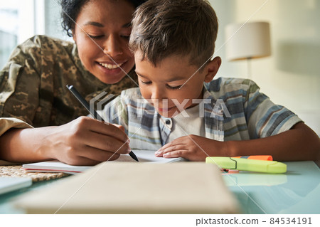 Black mother writing with her schoolboy son Black mother writing with her schoolboy son 84534191