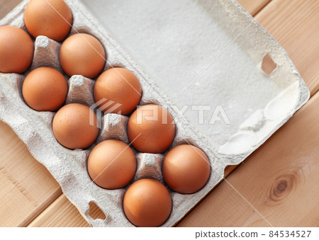 A few brown eggs among the cells of a large cardboard bag, a chicken egg as a valuable nutritious product, a tray for carrying and storing fragile eggs. A full package of eggs, an important food item 84534527