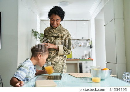 Woman in military uniform looking at her little son with love and tenderness 84534595