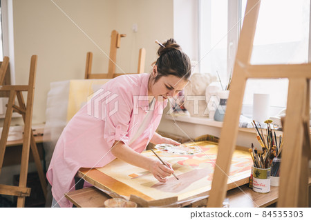 Art, creativity, hobby and creative occupation concept. Bringing creativity to life. Woman painting in art studio. Attractive female artist painting in workshop. Woman hobby, activity, profession 84535303