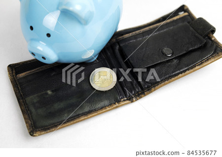 A coin of two euro cents on a light background, next to an empty wallet and a piggy bank. Crisis, default, inflation. A coin of two euro cents on a light background, next to an empty wallet and a piggy bank. Crisis, default, inflation. 84535677