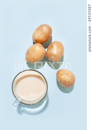 Potato milk. A cup with milk and potato tubers top view. Alternative plant milk Potato milk. A cup with milk and potato tubers top view. Alternative plant milk 84535987