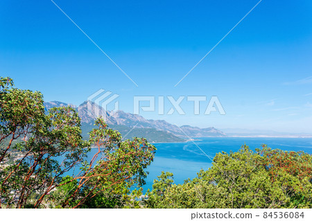 sea bay with a distant mountainous coast, view of mount Tahtali (Lycian Olympus) through the branches of trees in Antalya province, Turkey sea bay with a distant mountainous coast, view of mount Tahtali (Lycian Olympus) through the branches of trees in Antalya province, Turkey 84536084