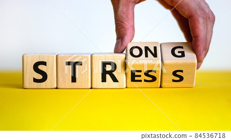 Strong stress symbol. Businessman turns wooden cubes with words 'strong stress'. Beautiful yellow table, white background, copy space. Business and strong stress concept. 84536718