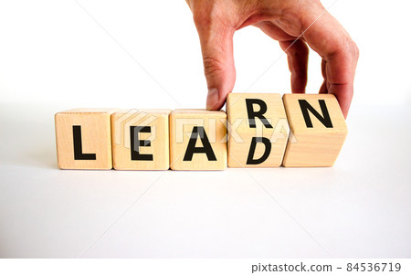 Learn and lead symbol. Businessman turns wooden cubes, changes the word 'learn' to 'lead'. Beautiful white table, white background. Business, educational, learn and lead concept. Copy space. 84536719