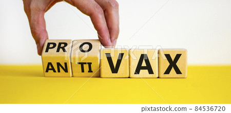 Pro-vax or anti-vax symbol. Doctor turns a cube, changes words 'anti-vax' to 'pro-vax'. Beautiful yellow table, white background. Copy space. Business, medical covid-19 pro-vax or anti-vax concept. Pro-vax or anti-vax symbol. Doctor turns a cube, changes words 'anti-vax' to 'pro-vax'. Beautiful yellow table, white background. Copy space. Business, medical covid-19 pro-vax or anti-vax concept. 84536720