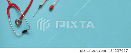 Top view of red stetoscope, syringe, and ampoules on blue background. Medicine concept. Banner size. 84537637