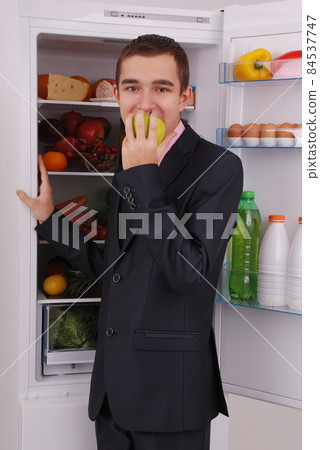 Teenager boy in suit and tie near the refrigerator Teenager boy in suit and tie near the refrigerator 84537747