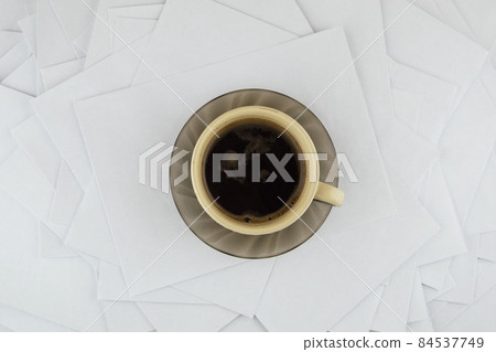 short break at the hard worker: a Cup of hot coffee and a brown glass saucer on a disorderly stack of papers short break at the hard worker: a Cup of hot coffee and a brown glass saucer on a disorderly stack of papers 84537749