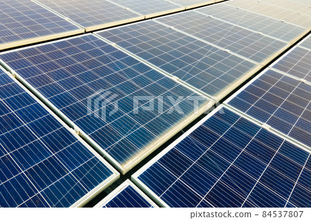 Aerial view of surface of blue photovoltaic solar panels mounted on building roof for producing clean ecological electricity. Production of renewable energy concept. 84537807
