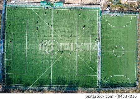 Aerial view of soccer players playing football on green sports stadium. Aerial view of soccer players playing football on green sports stadium. 84537810