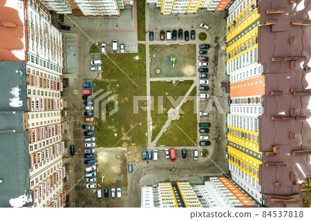 Aerial view of parked cars on parking lot between high apartment buildings. 84537818