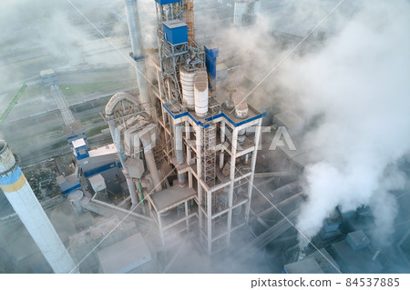 Aerial view of cement factory with high concrete plant structure and tower crane at industrial manufacturing site on foggy evening. Production and global industry concept. 84537885