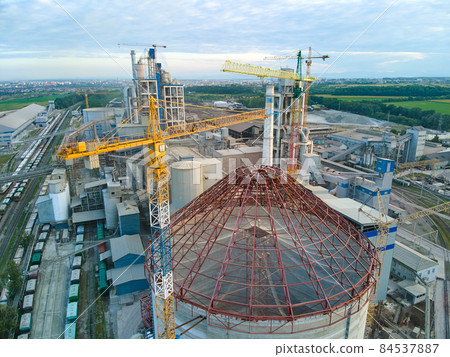 Aerial view of cement factory under construction with high concrete plant structure and tower cranes at industrial production area. Manufacture and global industry concept. 84537887