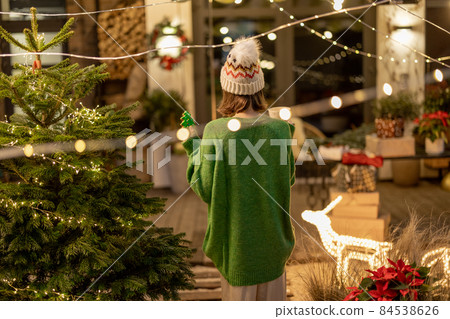 Woman with cookie and cup at New Year's decorated backyard Woman with cookie and cup at New Year's decorated backyard 84538626