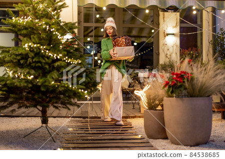 New Year's decorated backyard with a woman walking with presents New Year's decorated backyard with a woman walking with presents 84538685