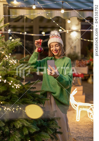 Woman decorating Christmas tree at backyard Woman decorating Christmas tree at backyard 84538702