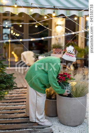 Woman decorates her yard for the New Year holidays Woman decorates her yard for the New Year holidays 84538738