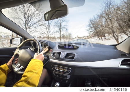 Modern car interior with driver female hands on steering wheel, winter snowy landscape outside. Safe driving concept. 84540156