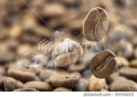 Flying fresh coffee beans as a background with copy space. Coffee beans falling down with white steam vapour. 84540203