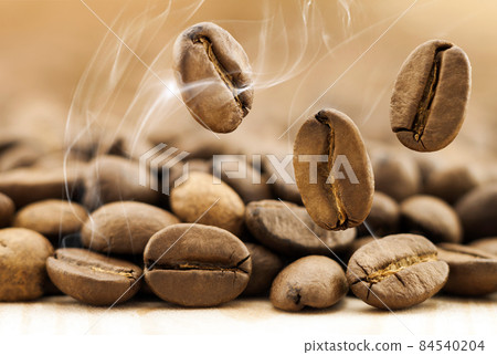 Flying fresh coffee beans as a background with copy space. Coffee beans falling down with white steam vapour. 84540204