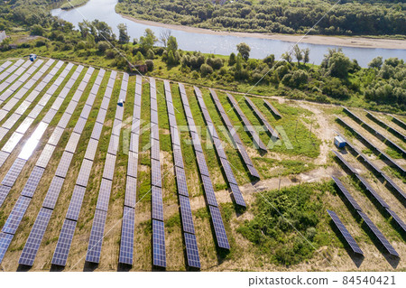 Aerial view of solar power plant on green field. Electric farm with panels for producing clean ecologic energy. 84540421