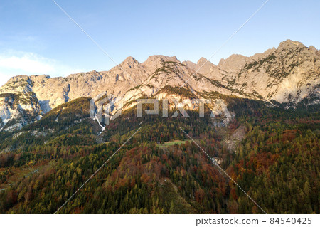 Aerial view of majestic european Alps mountains covered in evergreen pine forest in autumn. Aerial view of majestic european Alps mountains covered in evergreen pine forest in autumn. 84540425