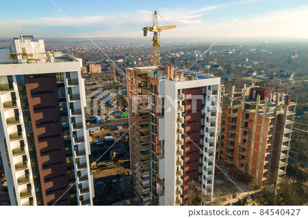 Aerial view of high tower crane and residential apartment buildings under construction. Real estate development. Aerial view of high tower crane and residential apartment buildings under construction. Real estate development. 84540427