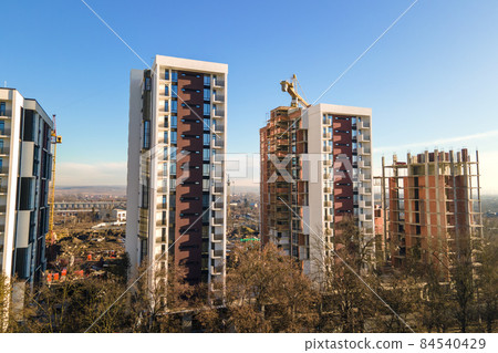 Aerial view of high tower crane and residential apartment buildings under construction. Real estate development. Aerial view of high tower crane and residential apartment buildings under construction. Real estate development. 84540429
