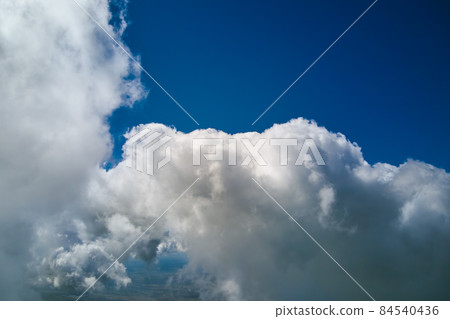 Aerial view from airplane window at high altitude of earth covered with white puffy cumulus clouds. 84540436