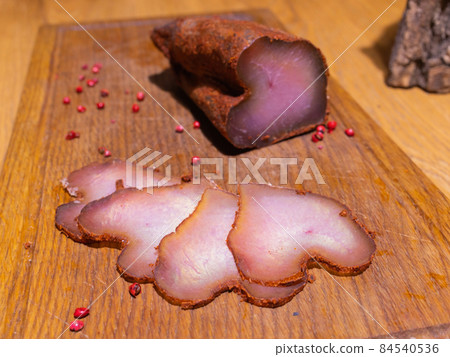 Sliced smoked gammon on a wooden table with addition of fresh herbs and aromatic spices. Sliced smoked gammon on a wooden table with addition of fresh herbs and aromatic spices. 84540536