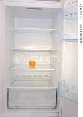 One mandarin in open empty refrigerator. 84540617