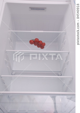 Cherry tomatoes in open empty refrigerator. 84540918