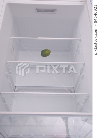 One lemon in open empty refrigerator. 84540923